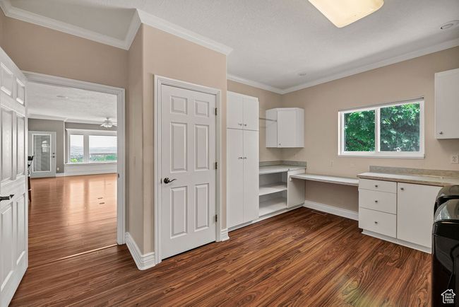 Unfurnished office with dark wood-style flooring, ornamental molding, built in study area, and baseboards | Image 25