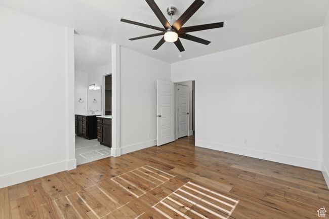 Unfurnished bedroom with light wood-style flooring, connected bathroom, and ceiling fan | Image 14