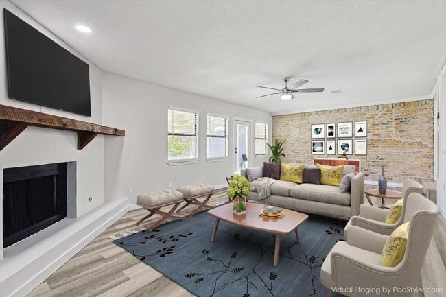 Living room featuring a textured ceiling, visible vents, a fireplace with raised hearth, wood finished floors, and a ceiling fan | Image 19