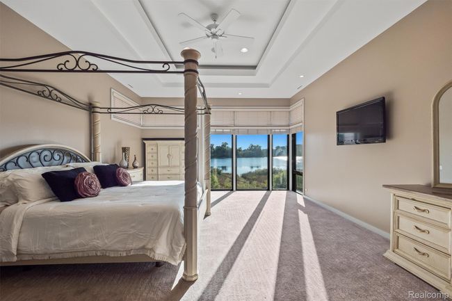 Bedroom with carpet flooring, a ceiling fan, a raised ceiling, access to outside, and recessed lighting | Image 44