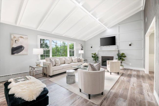 Living area with wood finished floors and a glass covered fireplace | Image 9