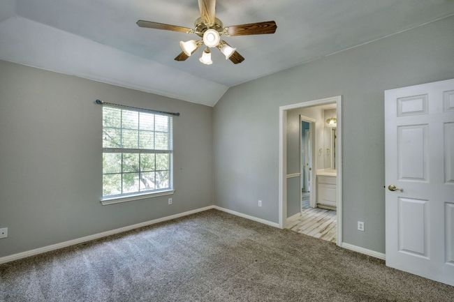 Unfurnished bedroom featuring carpet, lofted ceiling, a ceiling fan, connected bathroom, and baseboards | Image 23