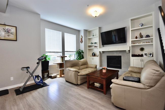 Living area with light wood-style floors, a fireplace, and built in shelves | Image 21