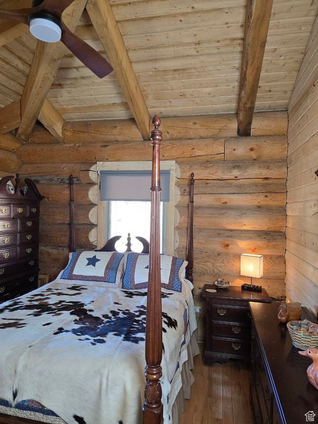 Bedroom with rustic walls, wood ceiling, wood finished floors, and vaulted ceiling with beams | Image 92