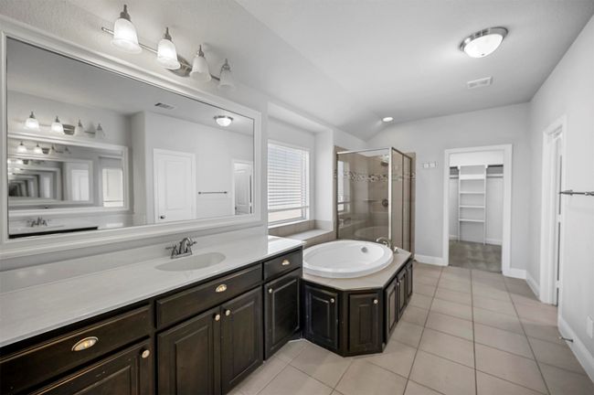 Full bathroom featuring vanity, a stall shower, tile patterned flooring, a spacious closet, and a garden tub | Image 27