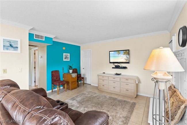 Living room with light tile patterned floors, crown molding, baseboards, and visible vents | Image 7