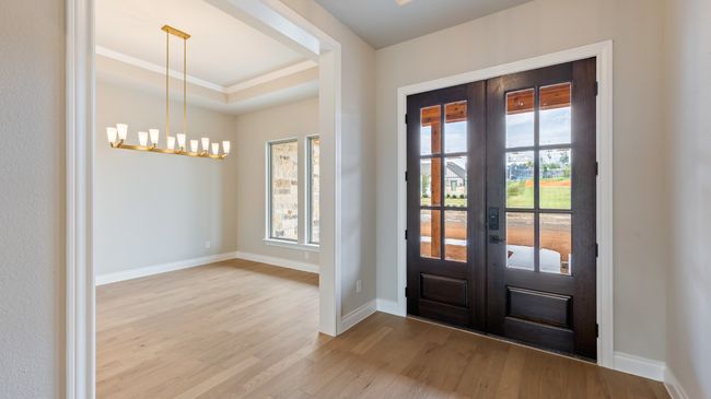 Doorway featuring wood finished floors, french doors, ornamental molding, a raised ceiling, and a chandelier | Image 13