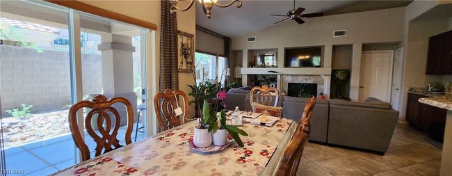 Dining room featuring light tile patterned floors, ceiling fan, a fireplace, and high vaulted ceiling | Image 6