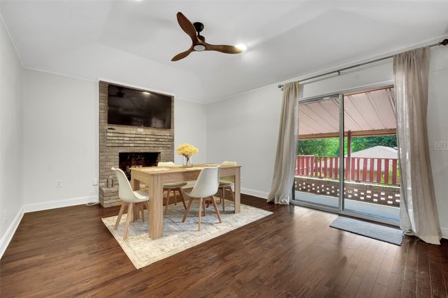 Dining area featuring wood finished floors, ceiling fan, and a brick fireplace | Image 10