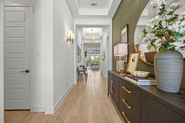 Hall with light wood-style flooring, a chandelier, and a tray ceiling | Image 5
