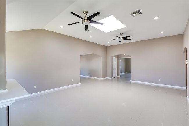 Empty room featuring ceiling fan, a skylight, arched walkways, recessed lighting, and vaulted ceiling | Image 7
