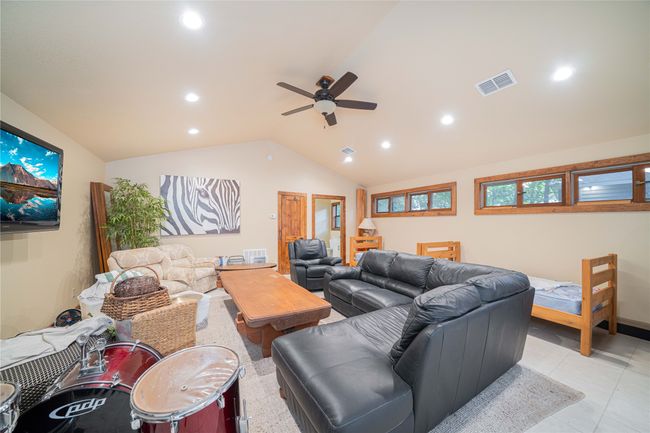 Living room with lofted ceiling, a ceiling fan, recessed lighting, and light tile patterned flooring | Image 39