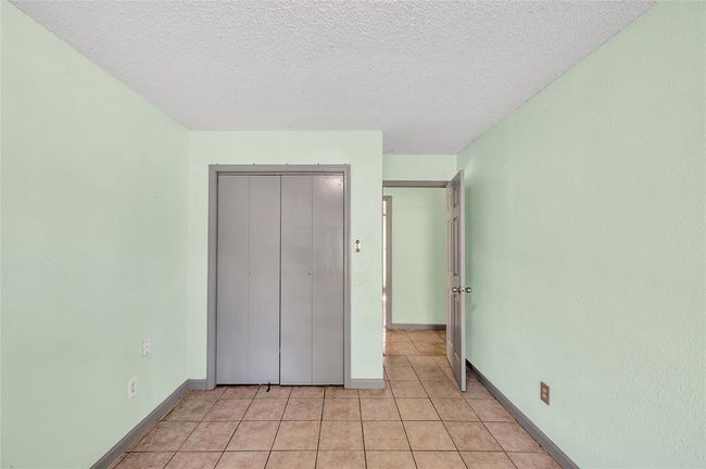 Discover the inviting second bedroom, featuring fresh paint, ample closet space, and easy-to-maintain tiled flooring. | Image 26