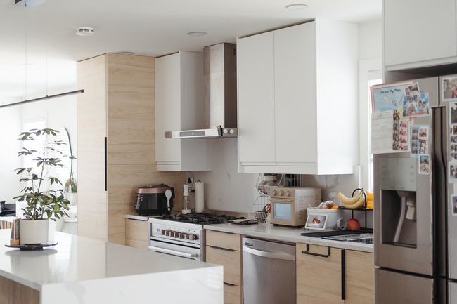 Kitchen featuring wall chimney exhaust hood, stainless steel appliances, modern cabinets, and light countertops | Image 4