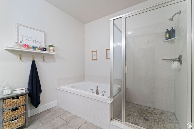 Bathroom with a bath, a shower stall, tile patterned floors, and baseboards | Image 16