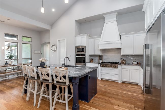 Kitchen featuring appliances with stainless steel finishes, high vaulted ceiling, a sink, custom exhaust hood, and dark stone countertops | Image 10