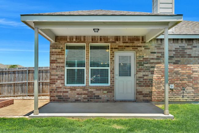 View of exterior entry with a patio area, brick siding, and a shingled roof | Image 27