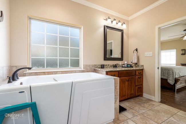 Bathroom featuring crown molding, connected bathroom, a garden tub, vanity, and baseboards | Image 23