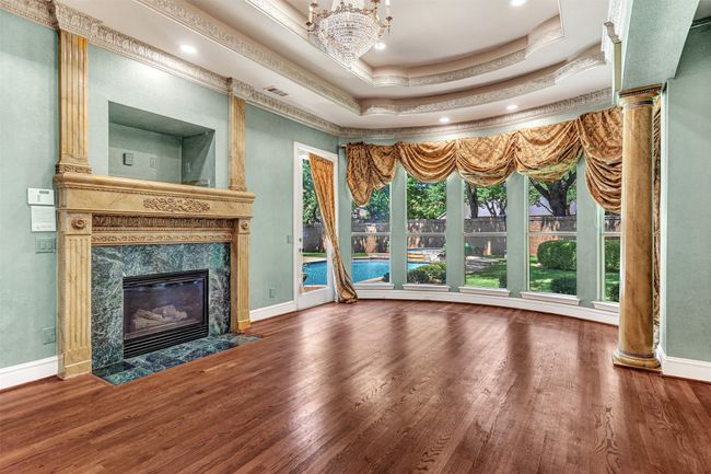 WOW! The primary suite is beyond compare! A wonderful gas log fireplace, bay window with pool views, columns, double tray ceiling with intricate crown molding...you can't help but feel like royalty! | Image 20