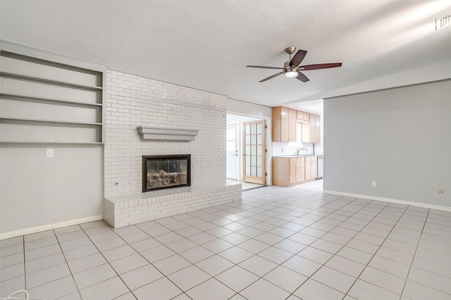 Large family room featuring a brick fireplace, ceiling fan, and easy flow to the kitchen and bonus room. | Image 9