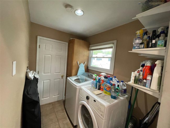 Laundry area featuring washing machine and dryer and light tile patterned floors | Image 19
