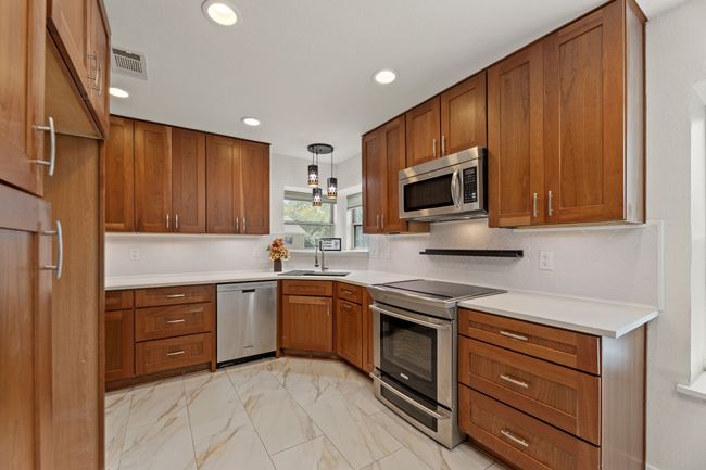 Kitchen with brown cabinetry, a sink, and stainless steel appliances | Image 9