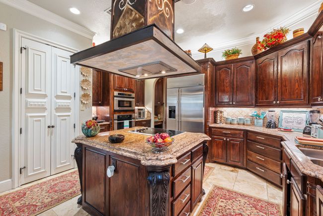 Kitchen featuring appliances with stainless steel finishes, ornamental molding, decorative backsplash, recessed lighting, and a kitchen island | Image 28
