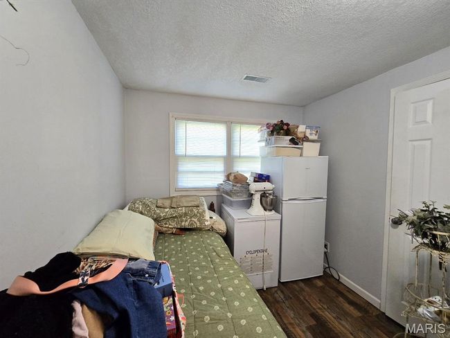 Bedroom with freestanding refrigerator, wood finished floors, and a textured ceiling | Image 16