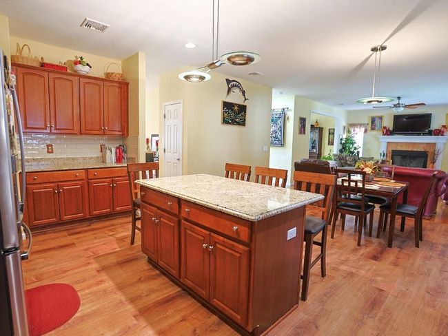 Kitchen featuring light wood-style flooring, a fireplace, a kitchen bar, a ceiling fan, and freestanding refrigerator | Image 9