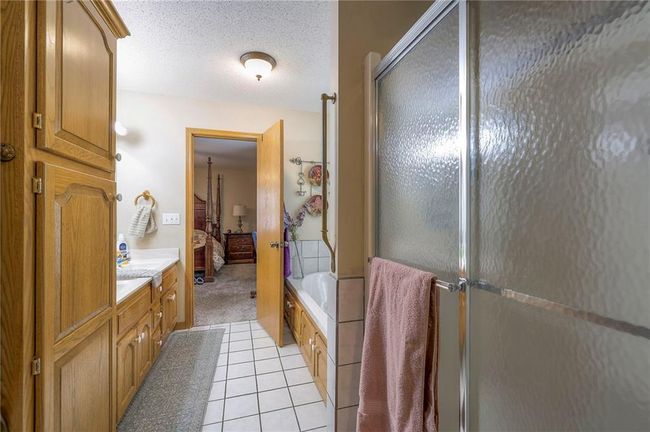 Ensuite bathroom with an enclosed shower, a tub, vanity, tile patterned flooring, and a textured ceiling | Image 19