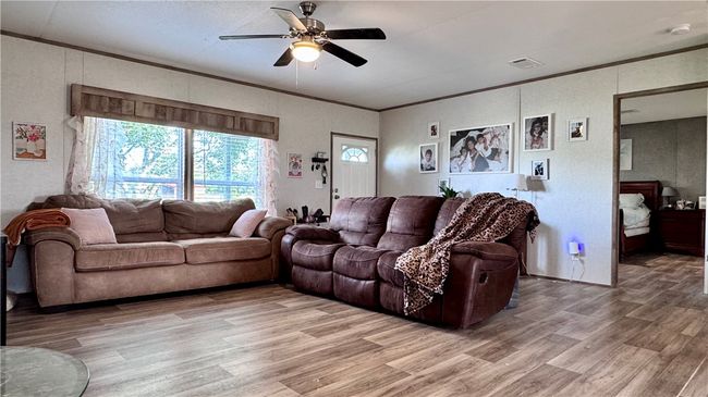 Living room with ornamental molding, ceiling fan, and light wood-style flooring | Image 12