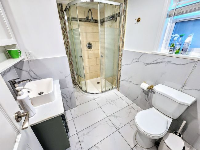 Full bathroom with marble finish floors, tile walls, toilet, a stall shower, and vanity | Image 36