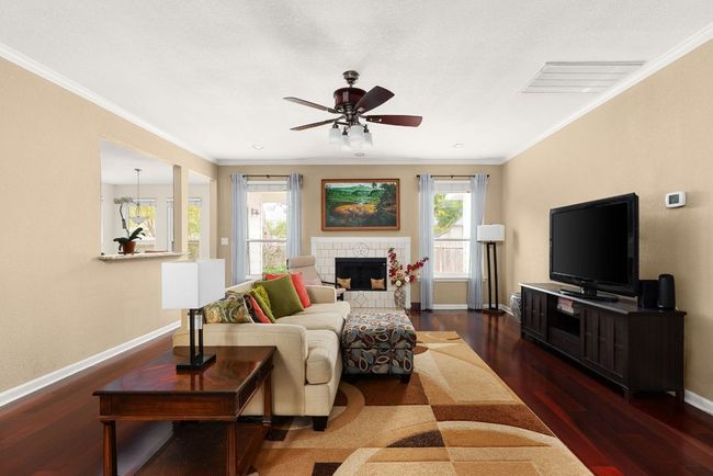 Living area with wood finished floors, baseboards, ornamental molding, and a healthy amount of sunlight | Image 15