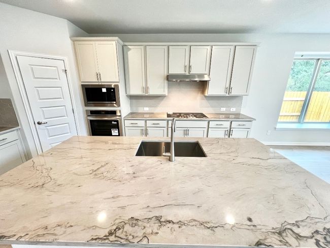 Kitchen with light stone counters, stainless steel appliances, tasteful backsplash, and wood finished floors | Image 6