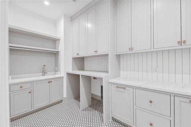 This spacious upstairs laundry room features custom cabinetry for ample storage and a convenient sink, making laundry tasks more efficient and organized. | Image 35