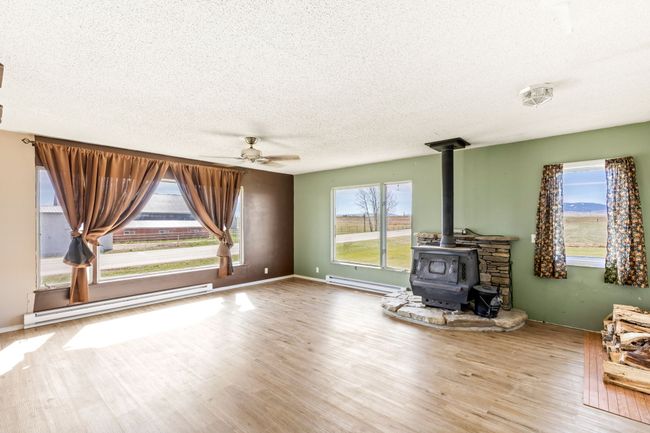 Unfurnished living room with baseboard heating, a wood stove, a ceiling fan, and a textured ceiling | Image 16