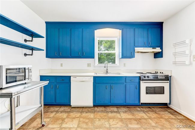 Kitchen with white appliances, under cabinet range hood, blue cabinetry, and light countertops | Image 29