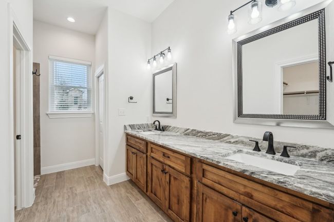 Bathroom with double vanity, wood plank tile floor, baseboards, and a sink | Image 21