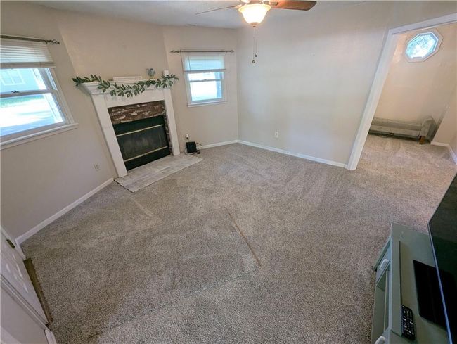 Unfurnished living room with ceiling fan, a tile fireplace, carpet, and baseboards | Image 10