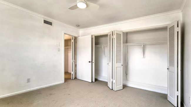 Unfurnished bedroom with ornamental molding, two closets, light carpet, and ceiling fan | Image 25