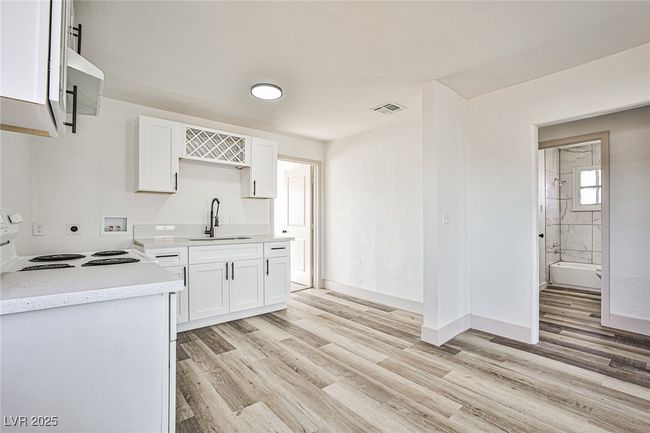 Kitchen featuring stove, light wood finished floors, and white cabinetry | Image 12