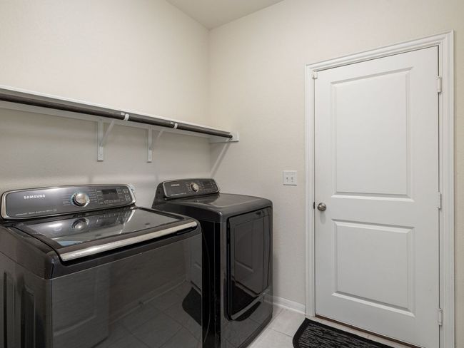 Washroom with washing machine and clothes dryer, light tile patterned flooring, and baseboards | Image 23