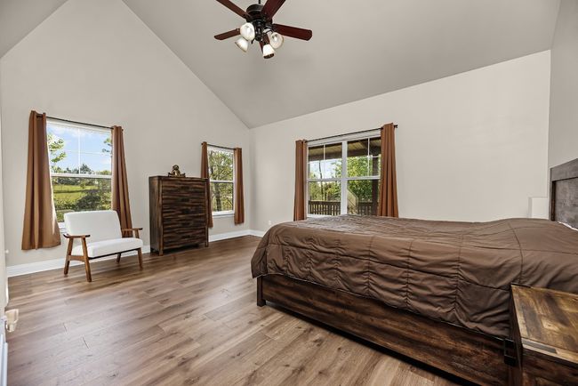 Bedroom featuring high vaulted ceiling, baseboards, a ceiling fan, and wood finished floors | Image 21
