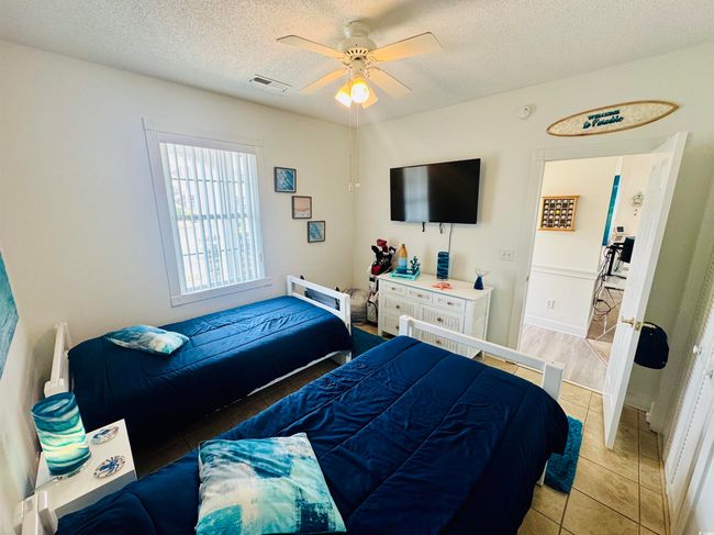 Bedroom featuring light tile patterned flooring, a textured ceiling, and a ceiling fan | Image 14