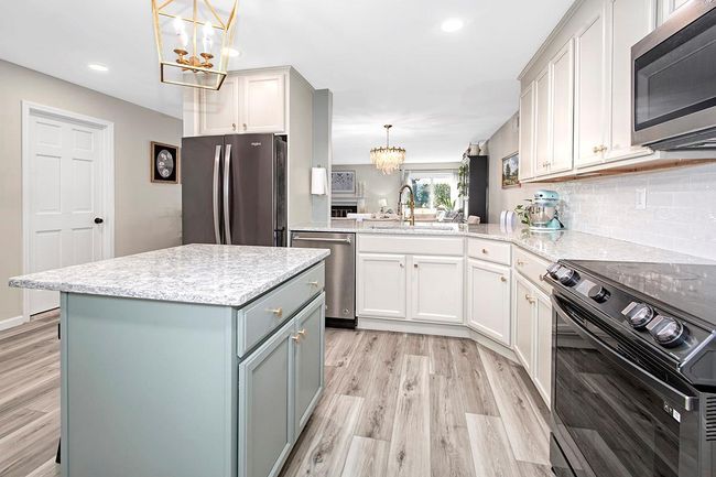 Kitchen featuring a sink, light wood-style flooring, a notable chandelier, and stainless steel appliances | Image 12
