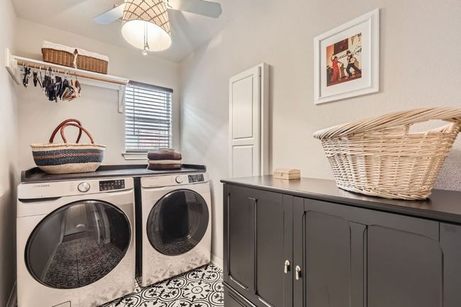 Laundry room with independent washer and dryer, a ceiling fan, cabinet space, tile patterned flooring, & Built In Ironing board | Image 19