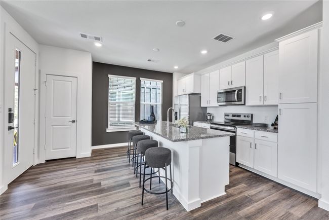 Kitchen with appliances with stainless steel finishes, an island with sink, a breakfast bar, and visible vents | Image 6