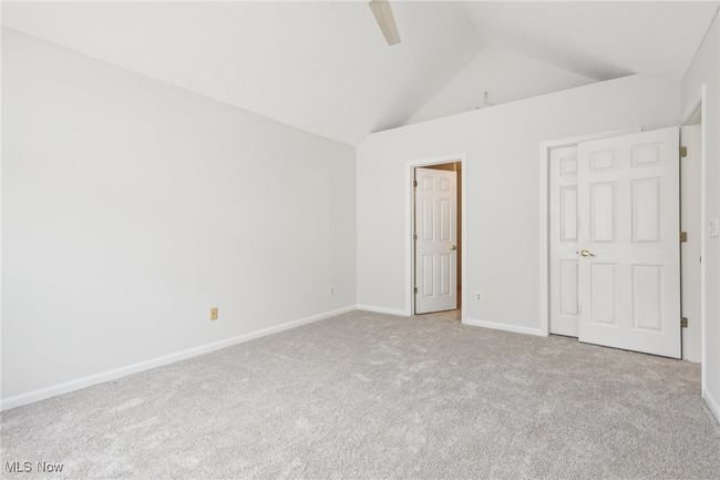 Master bedroom featuring vaulted ceiling, carpet flooring, Master bath, walk-in closet, and a ceiling fan | Image 17