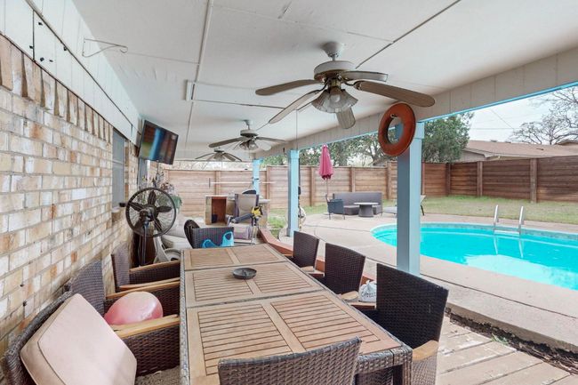 View of swimming pool with a patio, a fenced backyard, outdoor dining space, a fenced in pool, and ceiling fan | Image 30