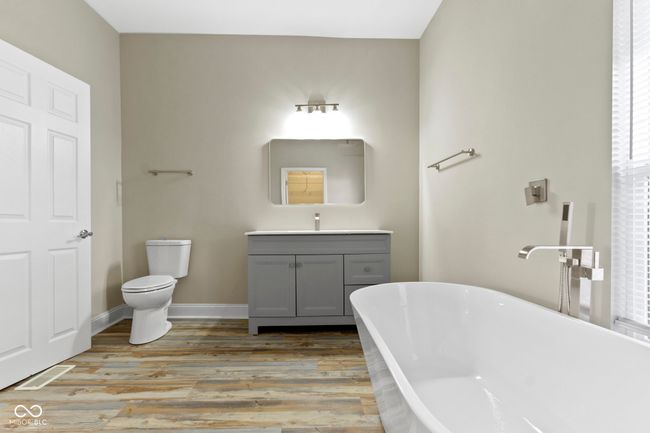 full bathroom with a freestanding tub, vanity, wood finished floors, toilet, and baseboards | Image 22